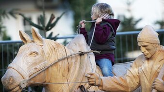 Kind auf einem lebensgroßen Holzpferd beim Adventmarkt in Strobl